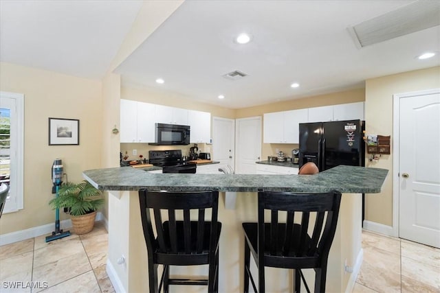 kitchen with dark countertops, visible vents, a breakfast bar area, and black appliances