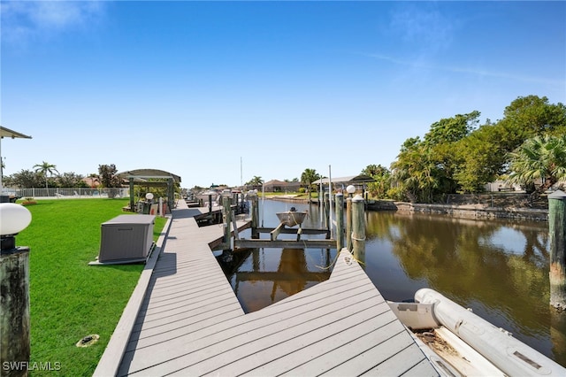 view of dock with a yard, a water view, and boat lift