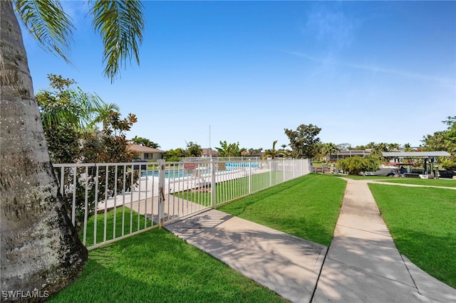 view of property's community with a swimming pool, fence, and a lawn