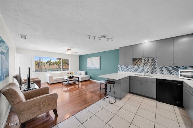 kitchen with a peninsula, gray cabinets, a sink, black dishwasher, and open floor plan