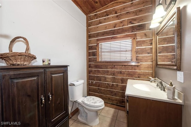 half bath with tile patterned floors, wood walls, toilet, and vanity