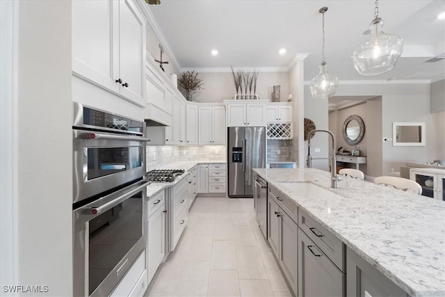 kitchen with light stone countertops, ornamental molding, decorative backsplash, stainless steel appliances, and a sink