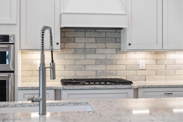 kitchen with white cabinets, appliances with stainless steel finishes, and backsplash