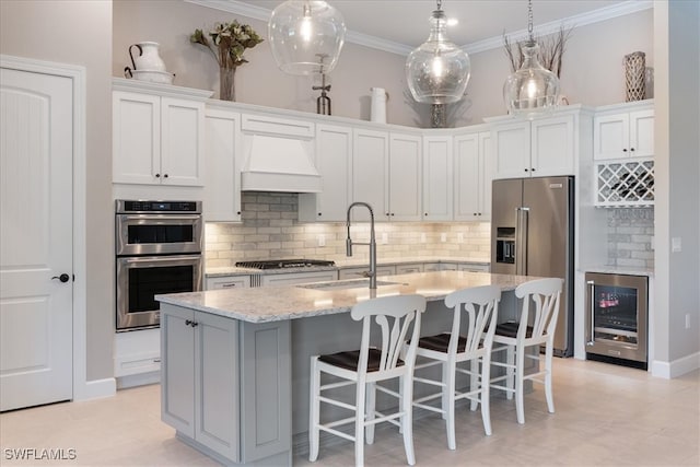 kitchen with crown molding, wine cooler, appliances with stainless steel finishes, custom exhaust hood, and a sink