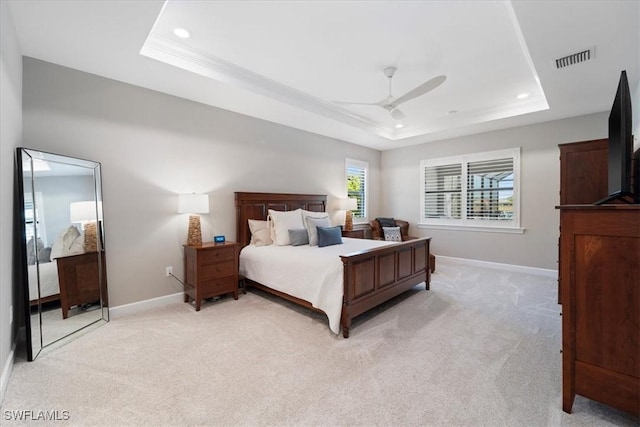 bedroom featuring baseboards, a raised ceiling, light colored carpet, and visible vents