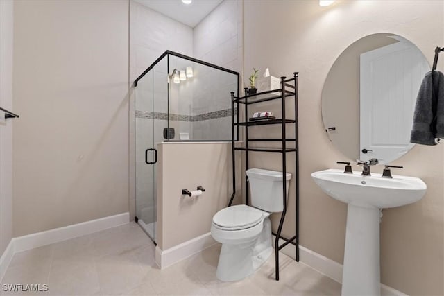 bathroom featuring baseboards, a stall shower, a sink, tile patterned floors, and toilet