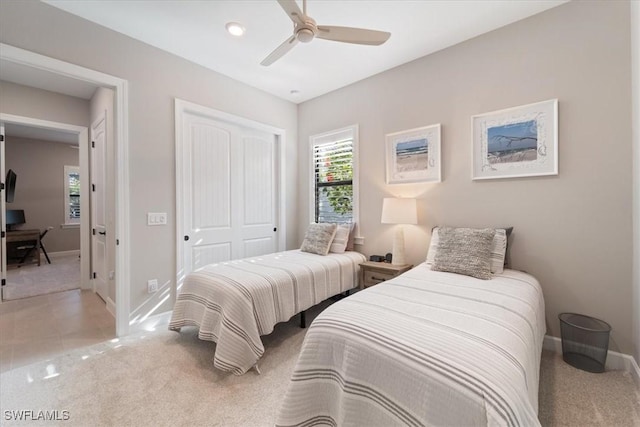 bedroom with baseboards, ceiling fan, light colored carpet, light tile patterned floors, and a closet