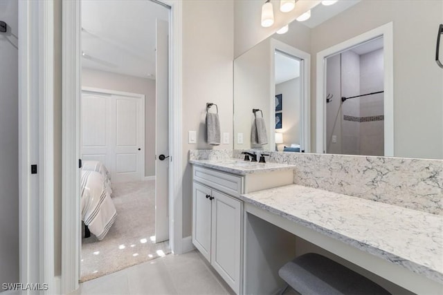 ensuite bathroom featuring tile patterned flooring, connected bathroom, baseboards, vanity, and a shower