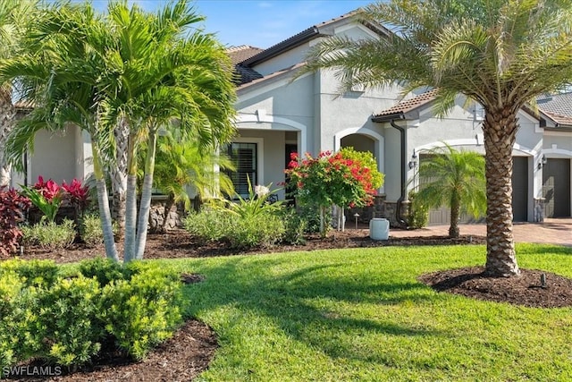 exterior space with stucco siding, an attached garage, a tile roof, and a front lawn