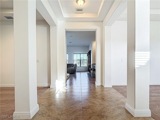 hallway with baseboards, visible vents, and ornate columns