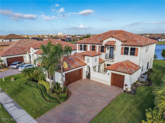 mediterranean / spanish house featuring a tile roof, stucco siding, decorative driveway, a garage, and a balcony