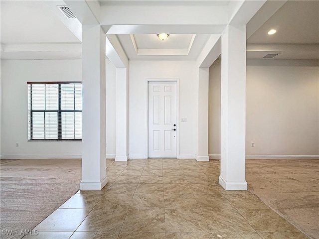 carpeted entrance foyer featuring a tray ceiling, decorative columns, baseboards, and visible vents