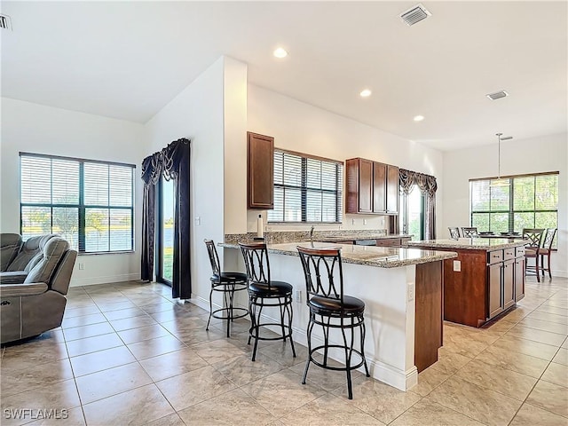 kitchen with a breakfast bar, a peninsula, open floor plan, and visible vents