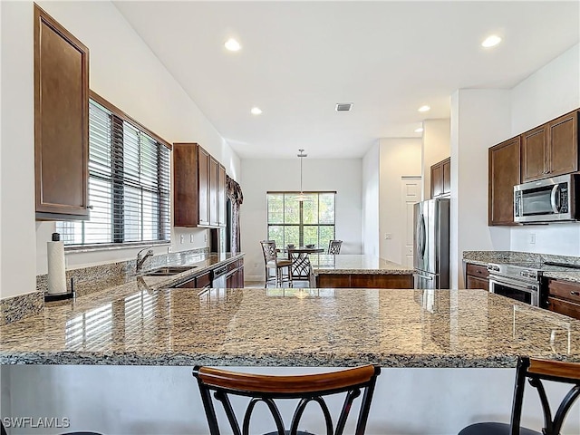 kitchen featuring visible vents, a sink, a kitchen island, appliances with stainless steel finishes, and a breakfast bar area