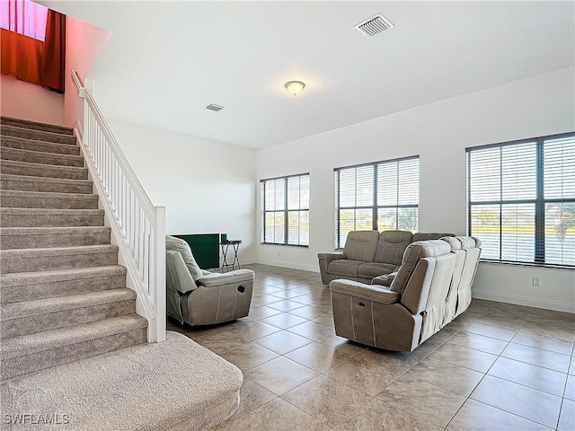 living room featuring stairs, light tile patterned flooring, baseboards, and visible vents