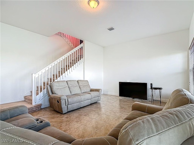 tiled living room featuring visible vents, stairs, and baseboards