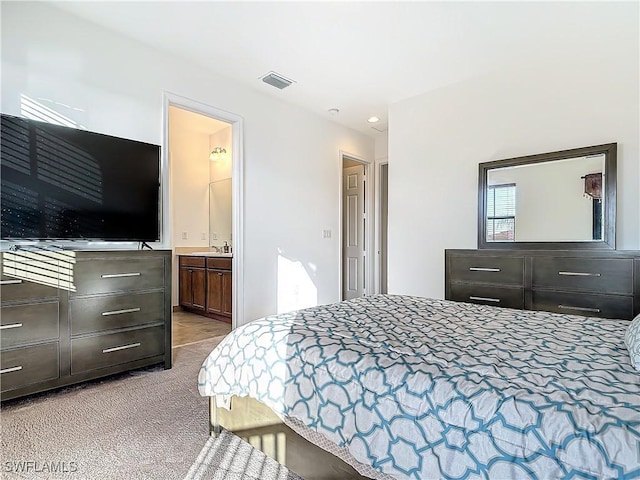 bedroom with visible vents, carpet flooring, ensuite bathroom, and a sink