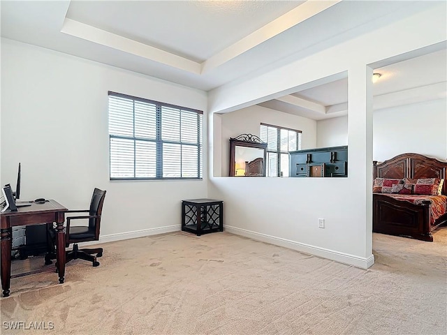 carpeted office space featuring a raised ceiling and baseboards