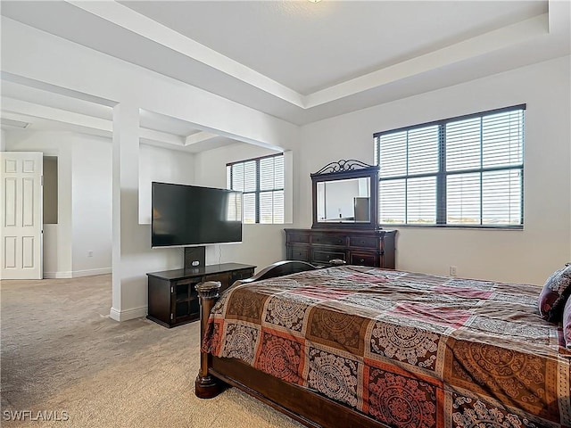 bedroom featuring a tray ceiling, baseboards, and light colored carpet