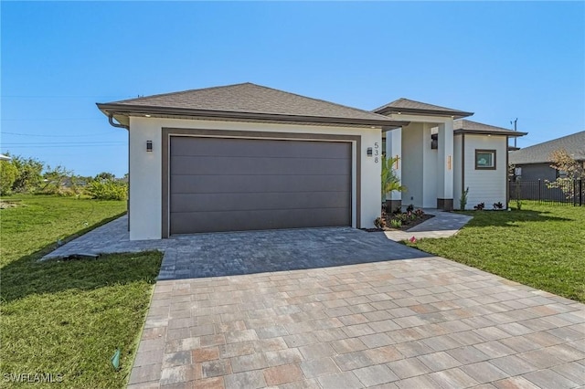 prairie-style house with decorative driveway, a front lawn, and stucco siding