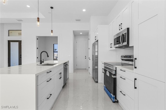 kitchen with a kitchen island with sink, a sink, light countertops, appliances with stainless steel finishes, and white cabinetry