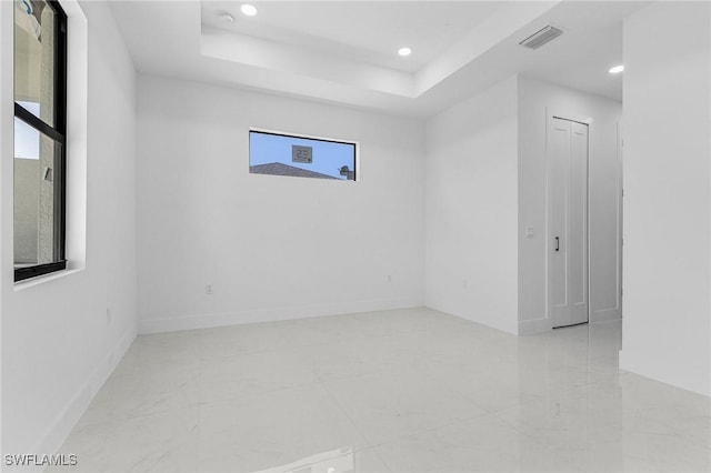 empty room featuring recessed lighting, baseboards, and a tray ceiling