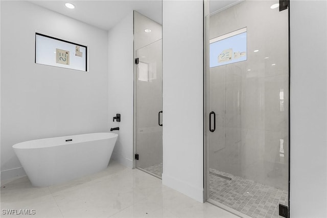 bathroom featuring a freestanding tub, baseboards, and a shower stall