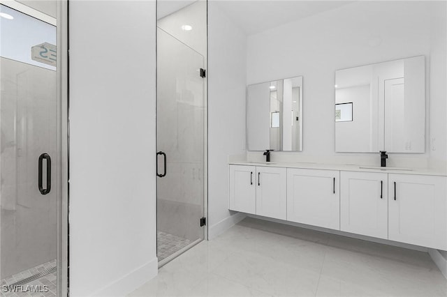 full bathroom featuring a sink, baseboards, a stall shower, and double vanity