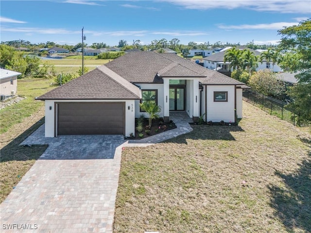 view of front of property with a front lawn, decorative driveway, fence, a shingled roof, and a garage