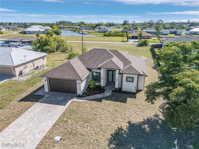 view of front of property with decorative driveway, a garage, roof with shingles, and stucco siding