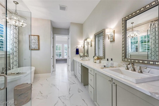 bathroom with a freestanding tub, marble finish floor, a sink, an inviting chandelier, and baseboards