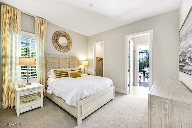 bedroom featuring a walk in closet, access to outside, light colored carpet, and baseboards