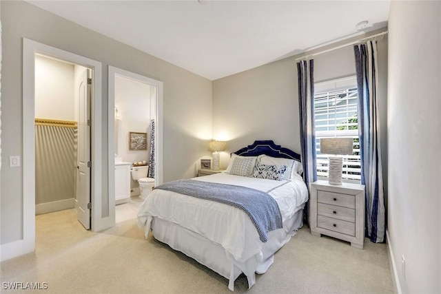 bedroom with light colored carpet, baseboards, and connected bathroom