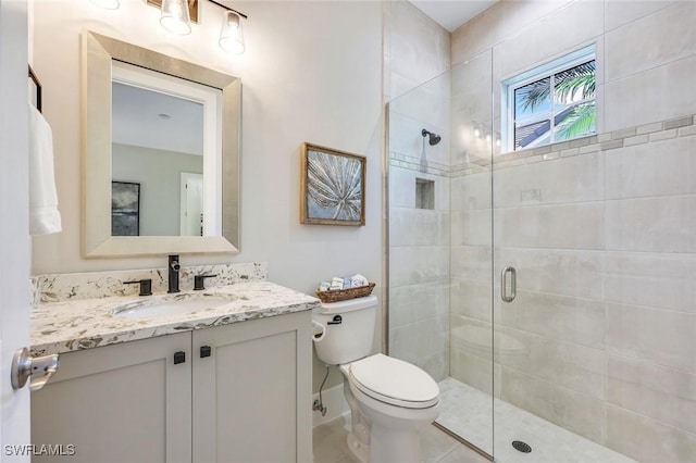 bathroom with toilet, a stall shower, vanity, and baseboards