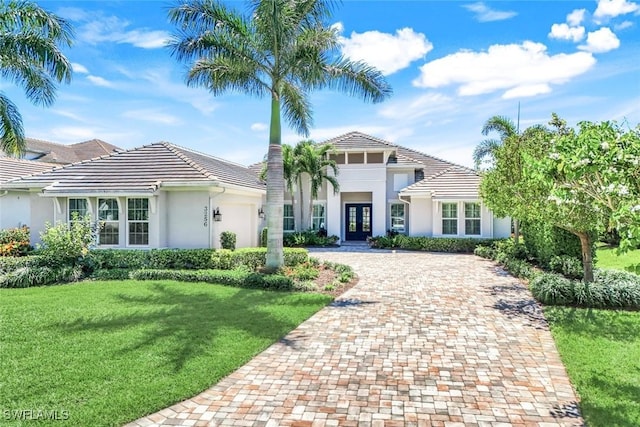 mediterranean / spanish home with stucco siding, an attached garage, a tile roof, and decorative driveway