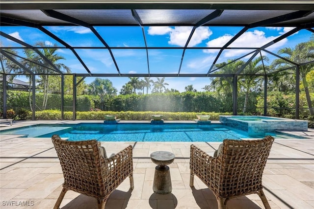 view of pool with a patio area, glass enclosure, and a pool with connected hot tub