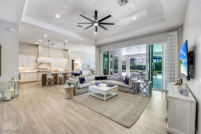 living area featuring a raised ceiling, light wood-style flooring, visible vents, and wooden ceiling