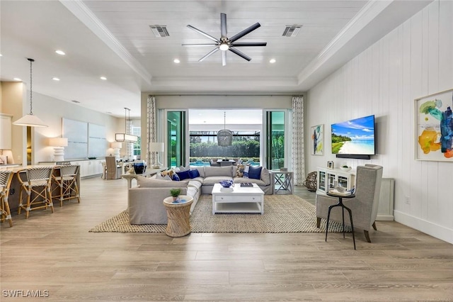 living area featuring light wood finished floors, visible vents, and a tray ceiling