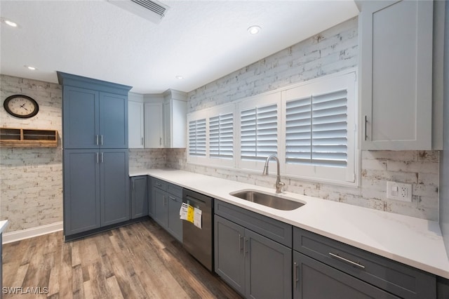 kitchen with wood finished floors, plenty of natural light, a sink, light countertops, and stainless steel dishwasher