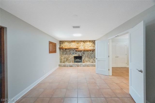 unfurnished living room featuring light tile patterned floors, visible vents, a fireplace, and baseboards