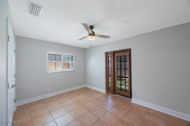 spare room featuring light tile patterned floors, visible vents, baseboards, and a ceiling fan