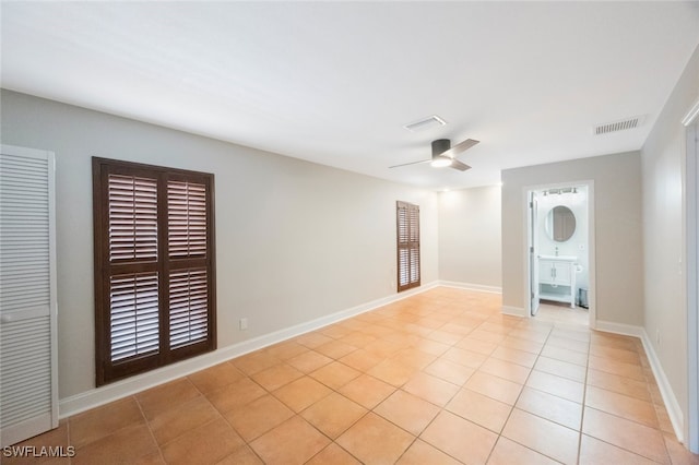 unfurnished room with light tile patterned floors, visible vents, baseboards, and ceiling fan