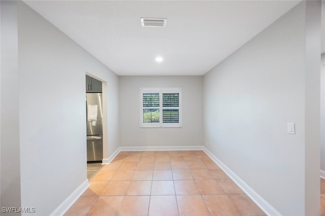 spare room featuring light tile patterned floors, visible vents, and baseboards