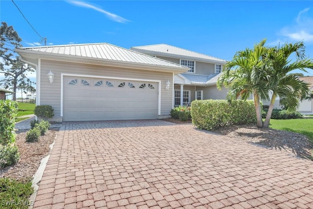 view of front of property featuring metal roof, decorative driveway, and a garage