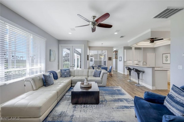 living area featuring crown molding, visible vents, light wood finished floors, and ceiling fan