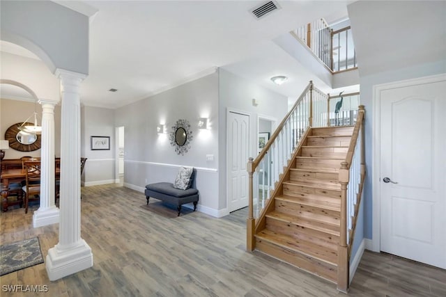 stairway featuring visible vents, baseboards, decorative columns, wood finished floors, and arched walkways