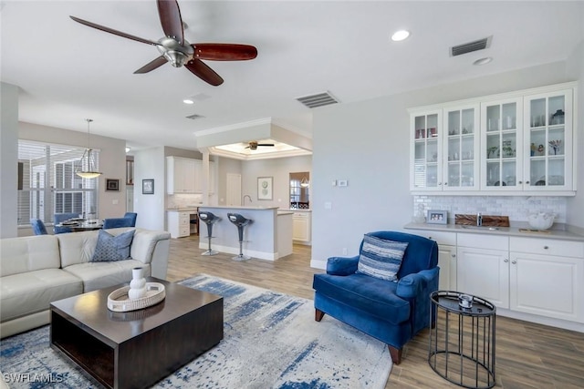 living room featuring visible vents, wood finished floors, and ceiling fan