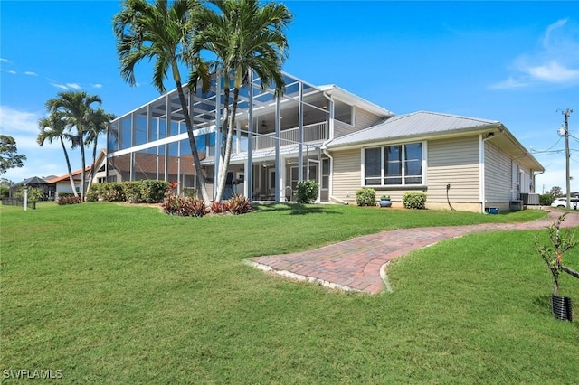 rear view of property with glass enclosure, cooling unit, and a lawn