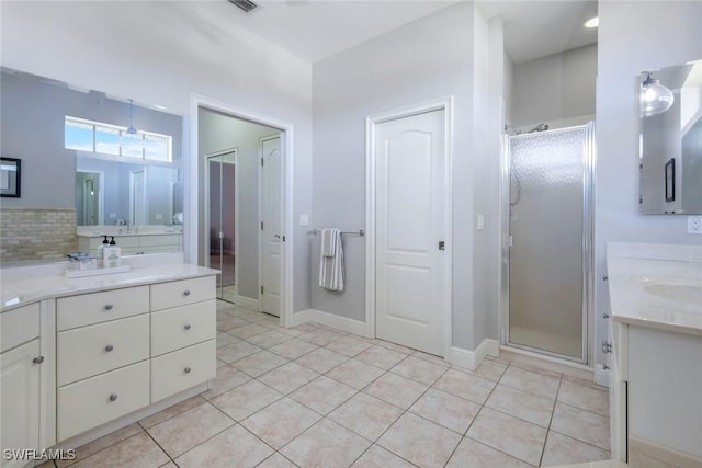 full bath featuring baseboards, two vanities, a stall shower, tile patterned flooring, and backsplash