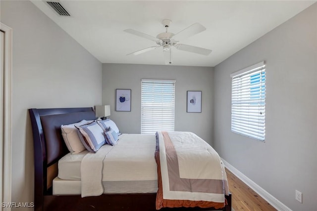 bedroom featuring visible vents, ceiling fan, baseboards, and wood finished floors